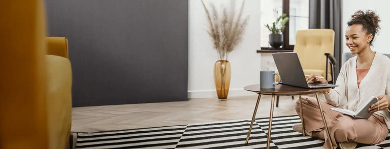 A sleek, dark gray laptop resting on a small round wooden table.